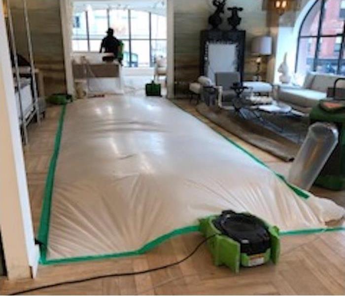 drying equipment and tarp over a water damaged hardwood floor
