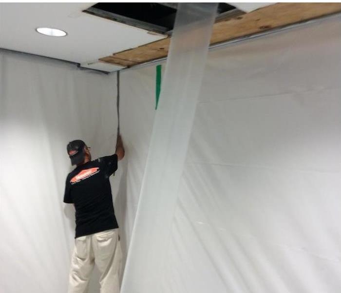 employee setting up a containment barrier in a mold damaged home